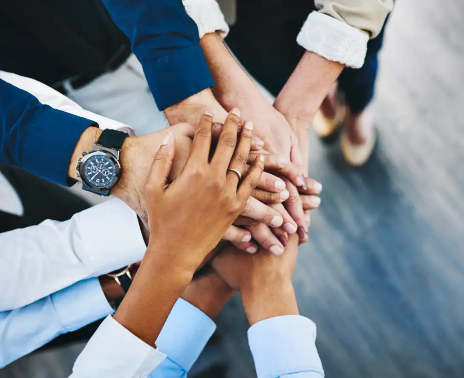 a group of people putting their hands together in a circle, signifying teamwork