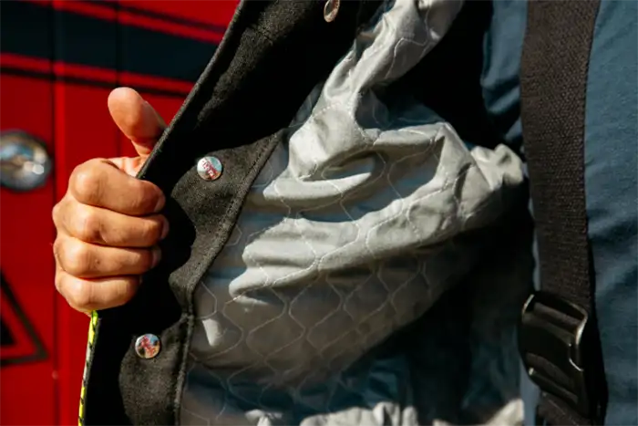 Close up image of a firefighter holding open the jacket of fire fighting gear