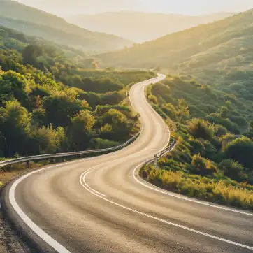 a winding road going through green rolling hills