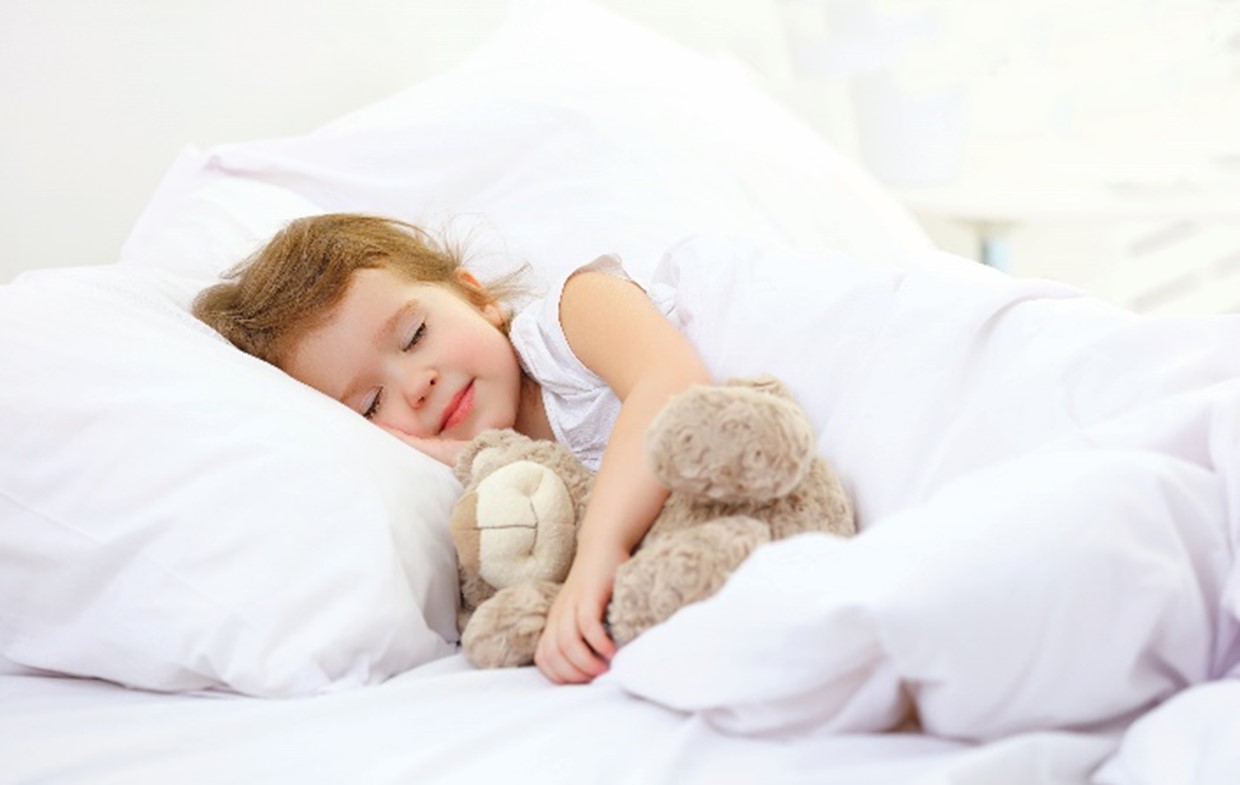 Child asleep in bed with stuffed animal