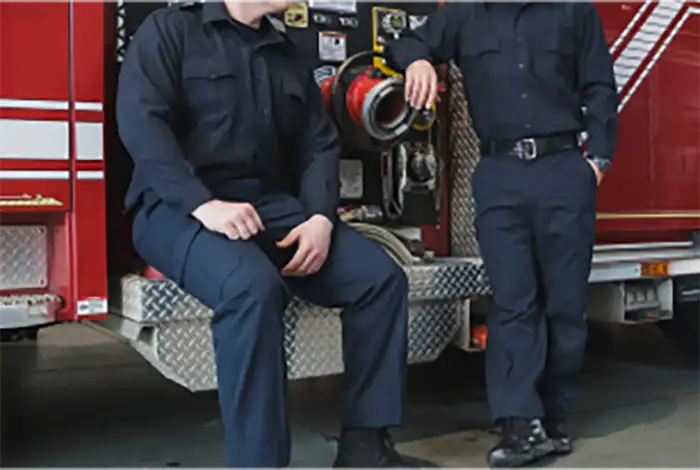 Photo of two firefighters talking in front of a fire truck